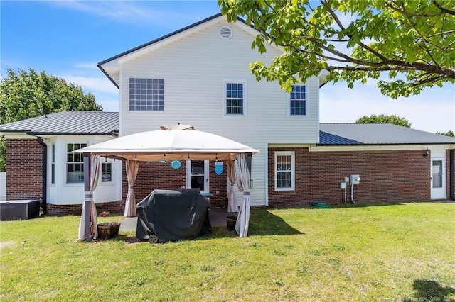 back of house featuring brick siding, a gazebo, a yard, and metal roof