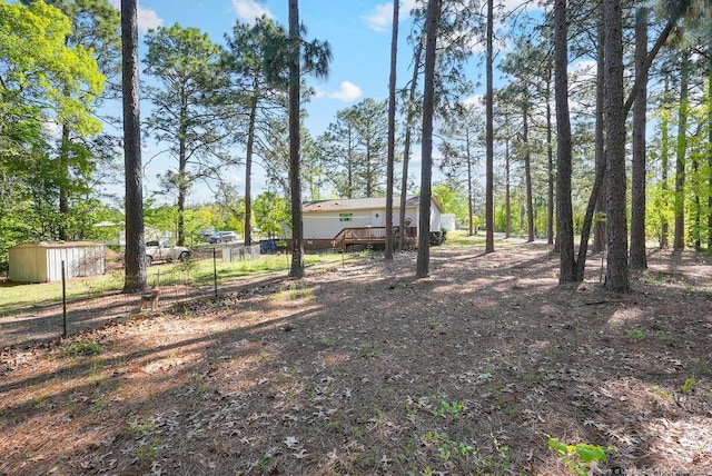 view of yard featuring a wooden deck, fence, an outbuilding, and a storage unit