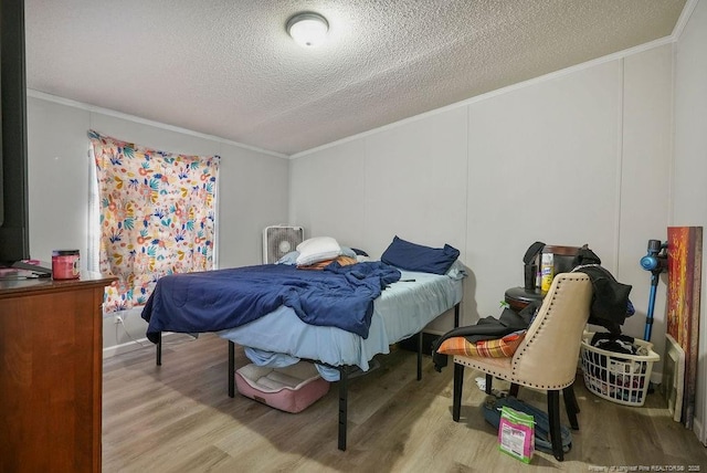 bedroom with crown molding, wood finished floors, and a textured ceiling