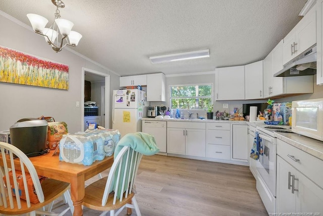 kitchen with a textured ceiling, under cabinet range hood, a chandelier, white appliances, and ornamental molding