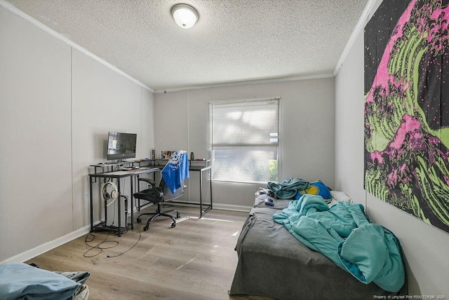 bedroom with wood finished floors, a textured ceiling, crown molding, and baseboards