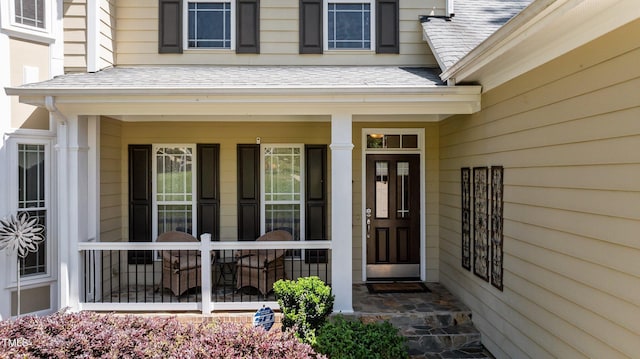 doorway to property with a porch and a shingled roof