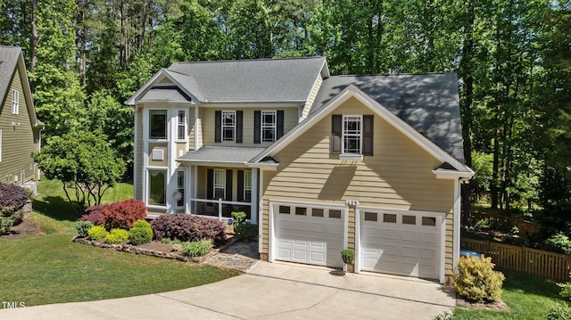 view of front facade with a garage, a front lawn, fence, a shingled roof, and driveway