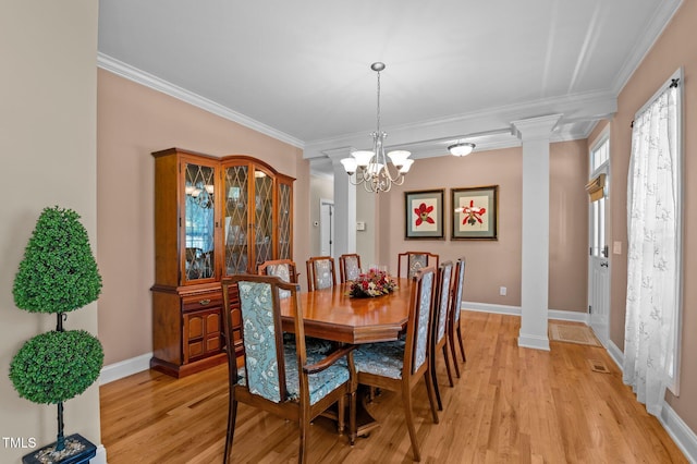 dining room featuring ornate columns, light wood-style flooring, crown molding, and baseboards