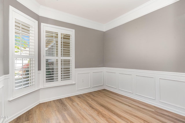 unfurnished room with wainscoting, crown molding, and light wood-style floors