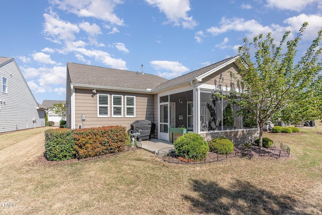 rear view of house with a lawn, a shingled roof, and a sunroom
