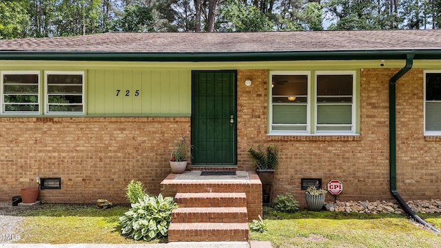 view of exterior entry featuring brick siding and a shingled roof