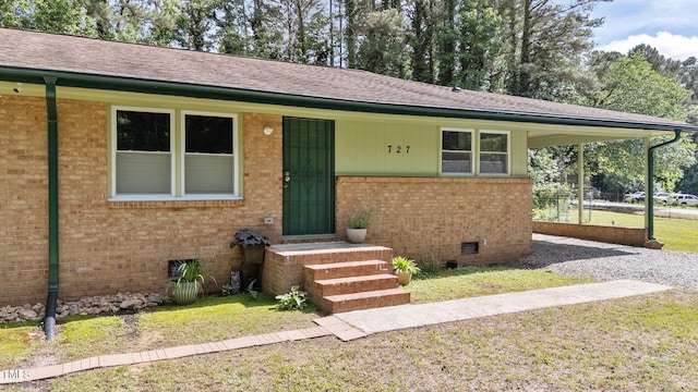 ranch-style home with brick siding, a front lawn, a shingled roof, and crawl space