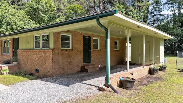 view of side of home with entry steps, brick siding, an attached carport, crawl space, and driveway