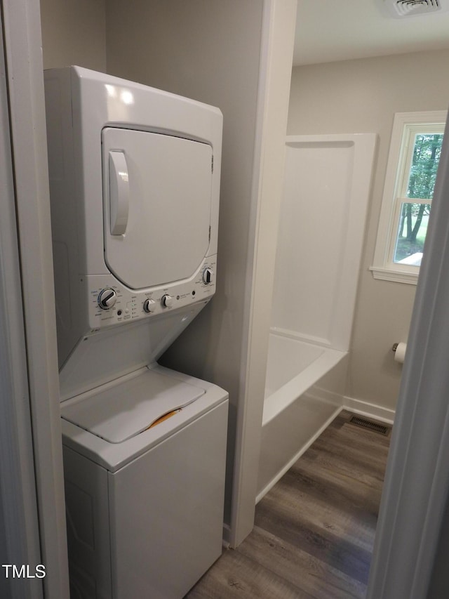 1165 John Mitchell Rd, Youngsville, NC 27596 - washroom with laundry area, stacked washer and clothes dryer, visible vents, wood finished floors, and baseboards
