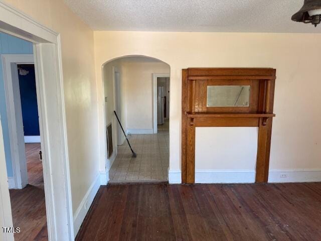 207 Harris St, Norlina, NC 27563 - hallway featuring arched walkways, a textured ceiling, baseboards, an upstairs landing, and wood finished floors