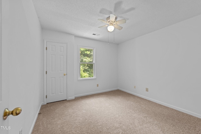 spare room with carpet floors, a ceiling fan, a textured ceiling, and baseboards