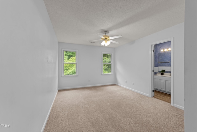 carpeted spare room with ceiling fan, baseboards, and a textured ceiling