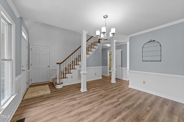 foyer featuring light wood-type flooring, a textured ceiling, stairway, a chandelier, and crown molding