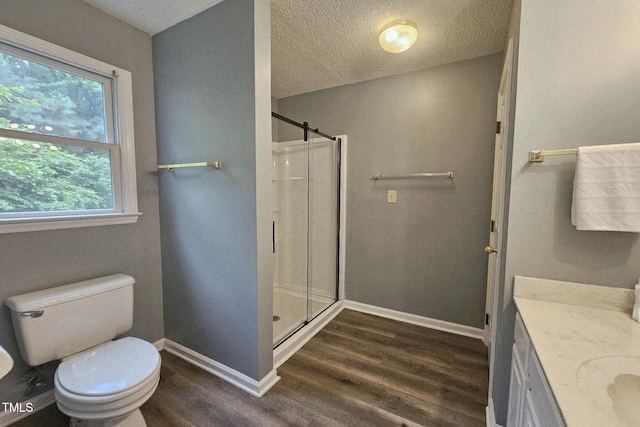 full bathroom featuring wood finished floors, a stall shower, a textured ceiling, baseboards, and toilet