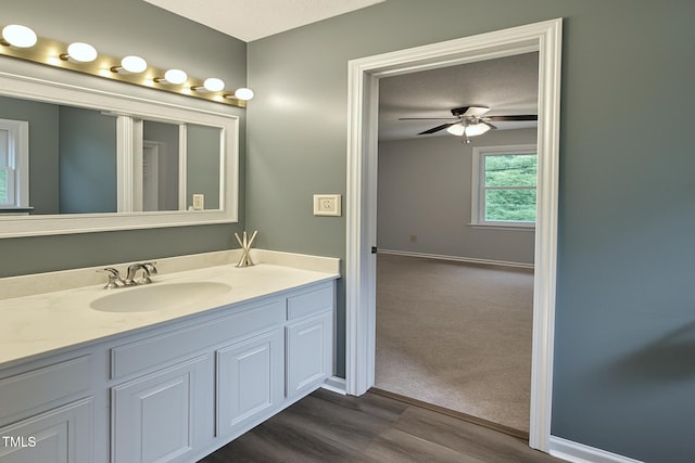 bathroom featuring ceiling fan, vanity, wood finished floors, and baseboards