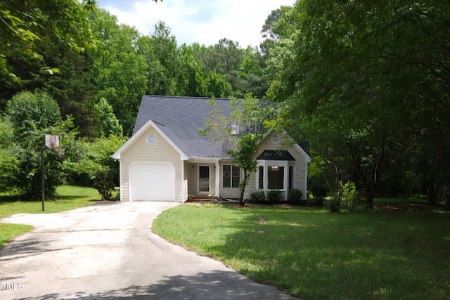 view of front facade featuring an attached garage, a front lawn, concrete driveway, and a wooded view