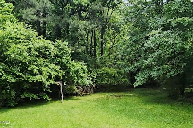 view of green lawn with a wooded view