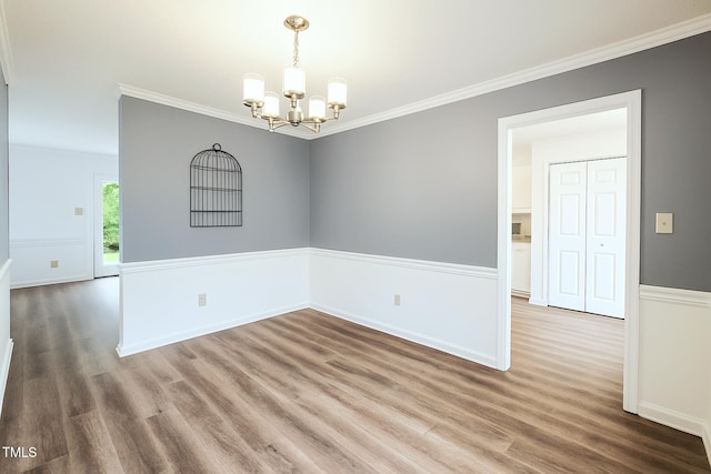 unfurnished room with a chandelier, wood finished floors, crown molding, and baseboards