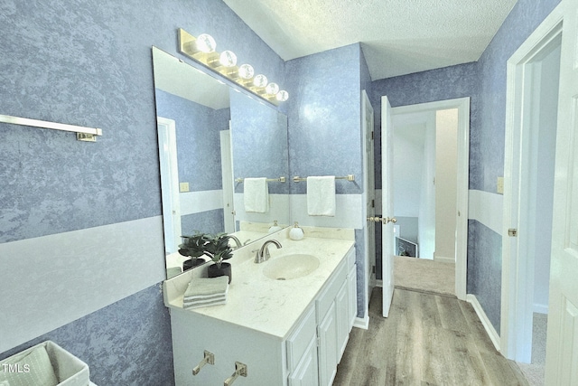 bathroom featuring wood finished floors, a textured ceiling, vanity, french doors, and wallpapered walls