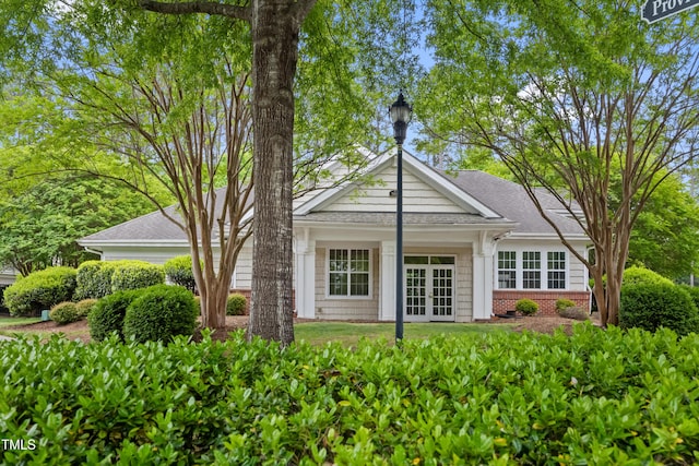 rear view of property with french doors, a shingled roof, and brick siding
