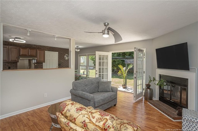 204 Bayfield Loop, Fayetteville, NC 28314 - living room featuring a glass covered fireplace, wood finished floors, ceiling fan, baseboards, and a textured ceiling