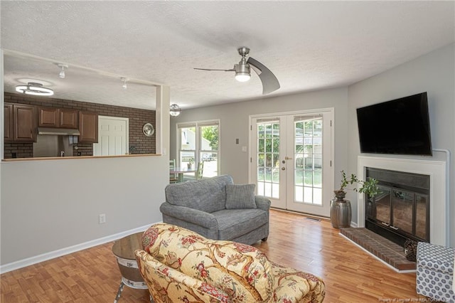204 Bayfield Loop, Fayetteville, NC 28314 - living area with light wood finished floors, ceiling fan, a textured ceiling, a glass covered fireplace, and french doors