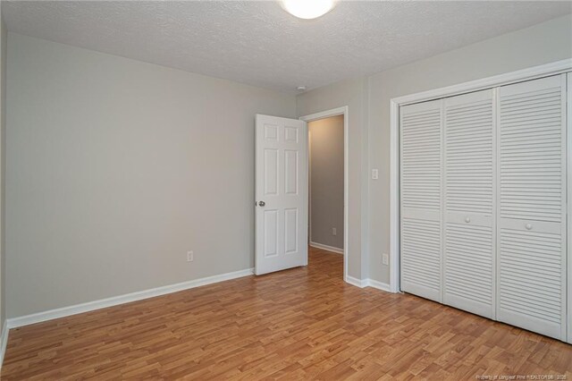 204 Bayfield Loop, Fayetteville, NC 28314 - unfurnished bedroom with light wood-style floors, a textured ceiling, baseboards, and a closet