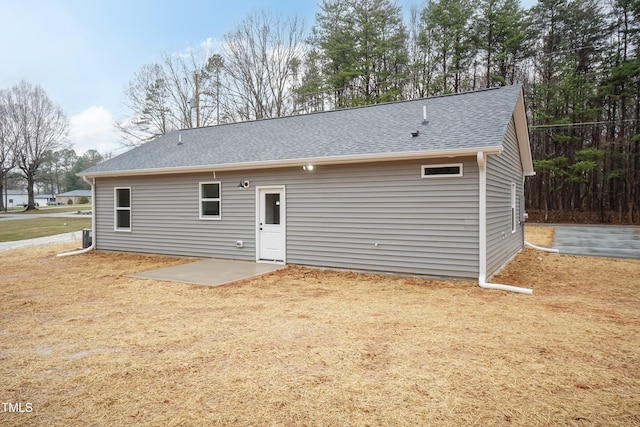 rear view of house featuring roof with shingles and a patio