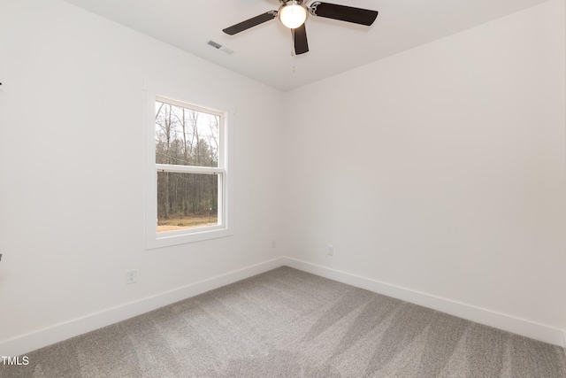 carpeted spare room featuring visible vents, a ceiling fan, and baseboards
