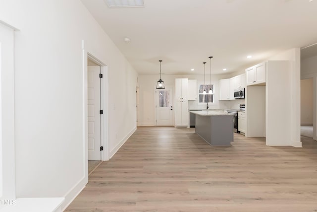 kitchen with light wood-style floors, stainless steel appliances, white cabinetry, a kitchen island, and recessed lighting