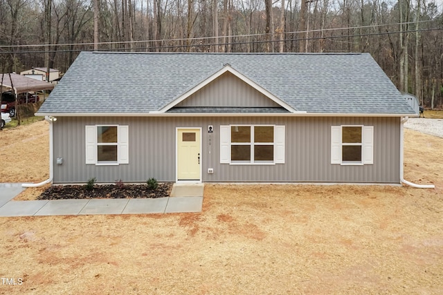 view of front of property featuring a shingled roof and a wooded view