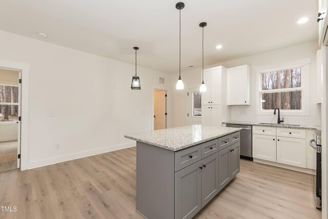 kitchen featuring light wood-type flooring, gray cabinetry, light stone countertops, dishwasher, and a kitchen island