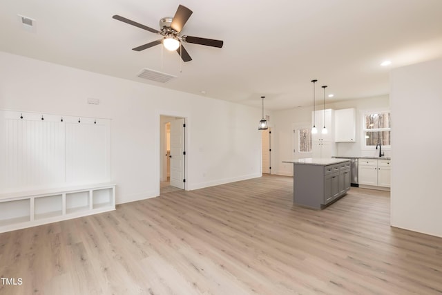 kitchen featuring a sink, visible vents, light wood-style floors, gray cabinetry, and a kitchen island