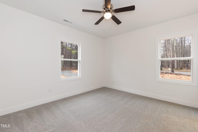 carpeted empty room featuring visible vents, a ceiling fan, and baseboards