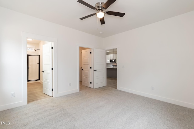 unfurnished bedroom featuring a spacious closet, light carpet, connected bathroom, and baseboards