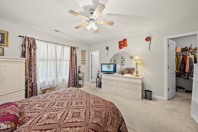 bedroom featuring a spacious closet, light carpet, visible vents, and baseboards