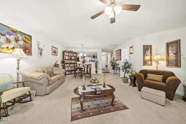 carpeted living area featuring baseboards and ceiling fan with notable chandelier