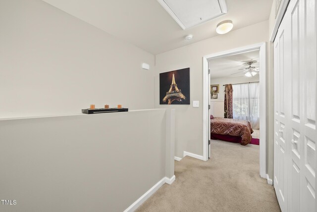 hall with attic access, light carpet, an upstairs landing, and baseboards