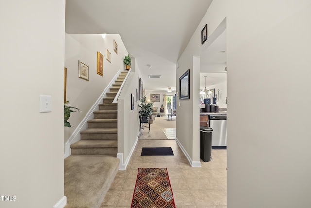 foyer entrance with light tile patterned flooring, a chandelier, baseboards, and stairs