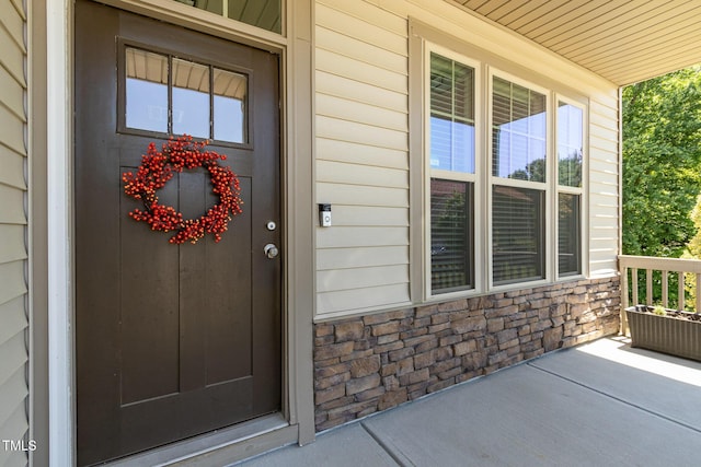 property entrance featuring a porch and stone siding