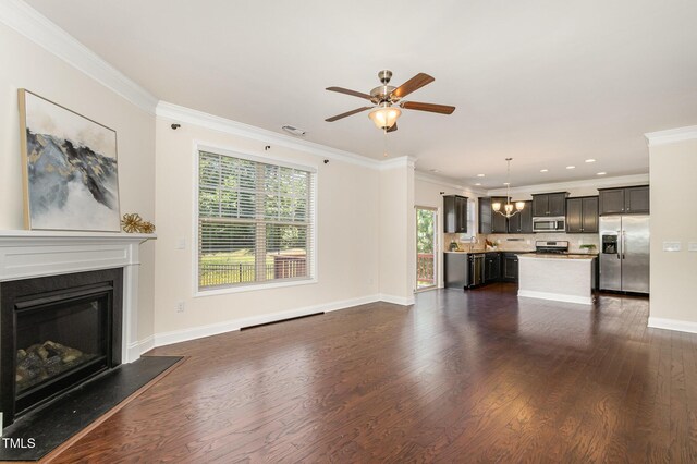 unfurnished living room featuring dark wood-type flooring, ornamental molding, a glass covered fireplace, and ceiling fan with notable chandelier
