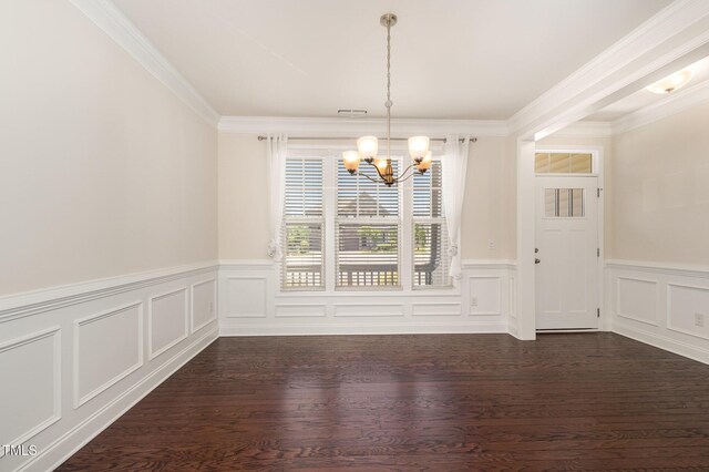 unfurnished dining area with crown molding, dark wood-style flooring, a decorative wall, a chandelier, and a wainscoted wall