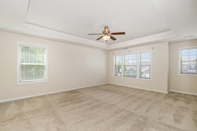 unfurnished room featuring crown molding, a ceiling fan, a tray ceiling, and light colored carpet