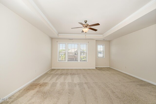 unfurnished room featuring ceiling fan, baseboards, ornamental molding, light carpet, and a tray ceiling