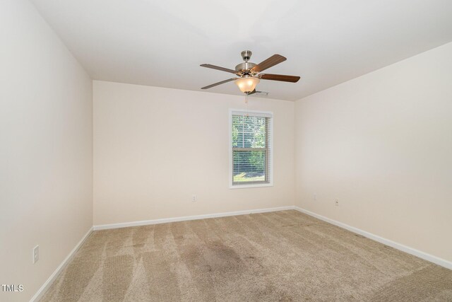 spare room featuring baseboards and light carpet