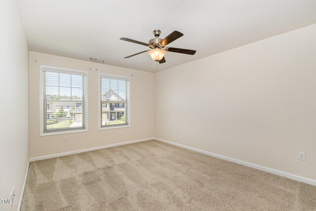 carpeted spare room with baseboards, a ceiling fan, and visible vents