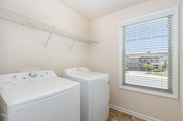 laundry area with laundry area, stone finish floor, washing machine and dryer, and baseboards