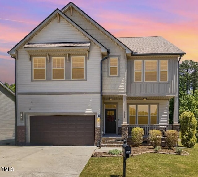 craftsman-style home featuring a porch, a front lawn, concrete driveway, an attached garage, and stone siding