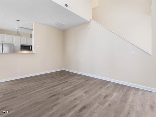 unfurnished living room with light wood-style flooring and baseboards